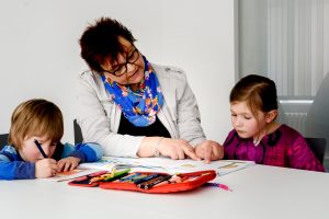 Hilfskraft zeigt Mädchen etwas in ihrem Heft