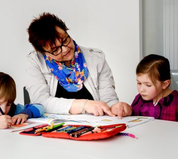 Hilfskraft zeigt Mädchen etwas in ihrem Heft