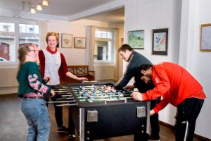 vier personen spielen an einem Kicker