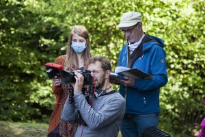 drei Personen, eine hält Kamera und filmt, eine hält Skript