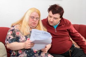 Frau mit Behinderung und ihr Mann lesen einen Brief 