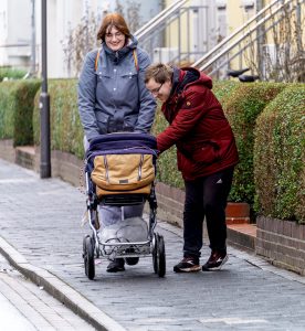 Paar geht mit Kinderwagen spazieren 