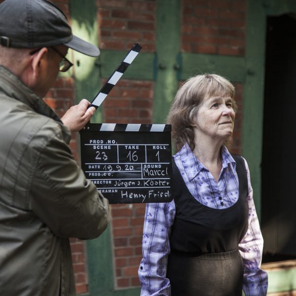 Mann hält Filmklappe vor alte Frau