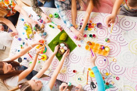Man sieht Kinderhände, die mit Oster-Dekoration hantieren