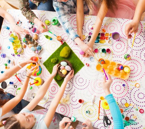 Man sieht Kinderhände, die mit Oster-Dekoration hantieren