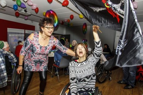 Zwei Frauen tanzen, eine davon sitzt im Rollstuhl.