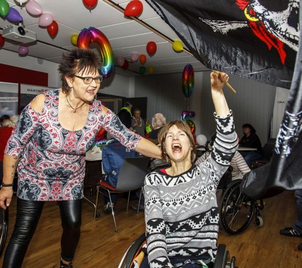 Zwei Frauen tanzen, eine davon sitzt im Rollstuhl.