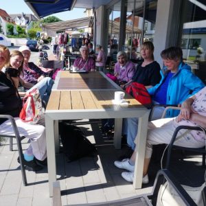 Fröhliche Seniorinnen und Senioren im Außenbereich eines Cafés.