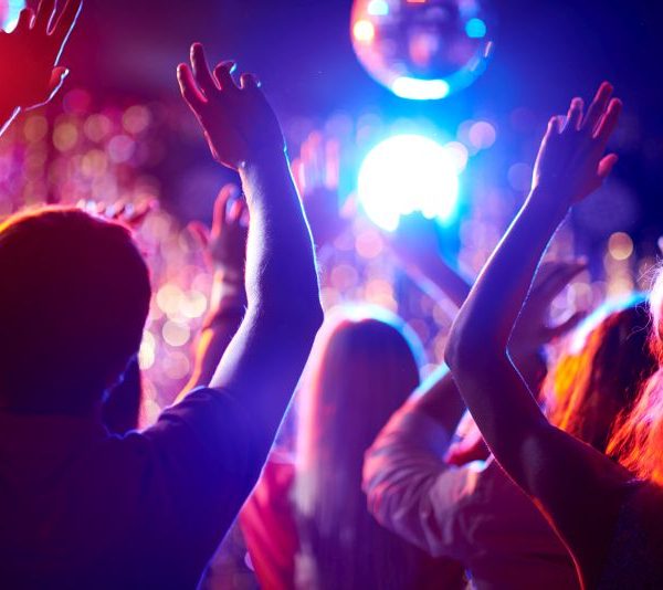 Menschen tanzen mit erhobenen Armen in einer Disco