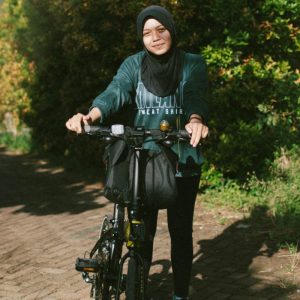 Eine Frau mit KOpftuch auf einem Fahrrad.