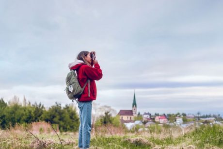 Frau oder Mädchen fotografiert in der Natur. Im Hintergrund ist eine Kleinstadt zu sehen.