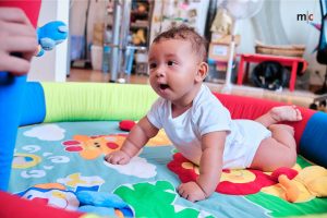 Ein Baby liegt auf einer bunten Spieldecke