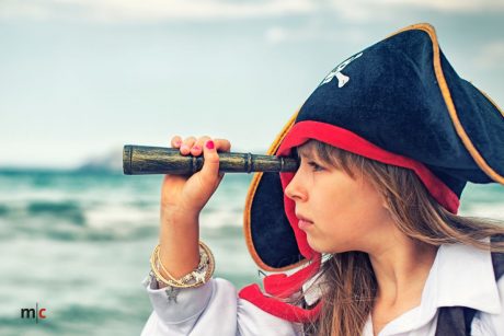 Ein Mädchen als Pirat verkleidet schaut durch ein Fernglas.