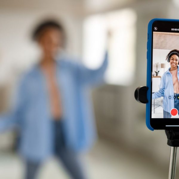 Cheerful black woman filming video on cellphone