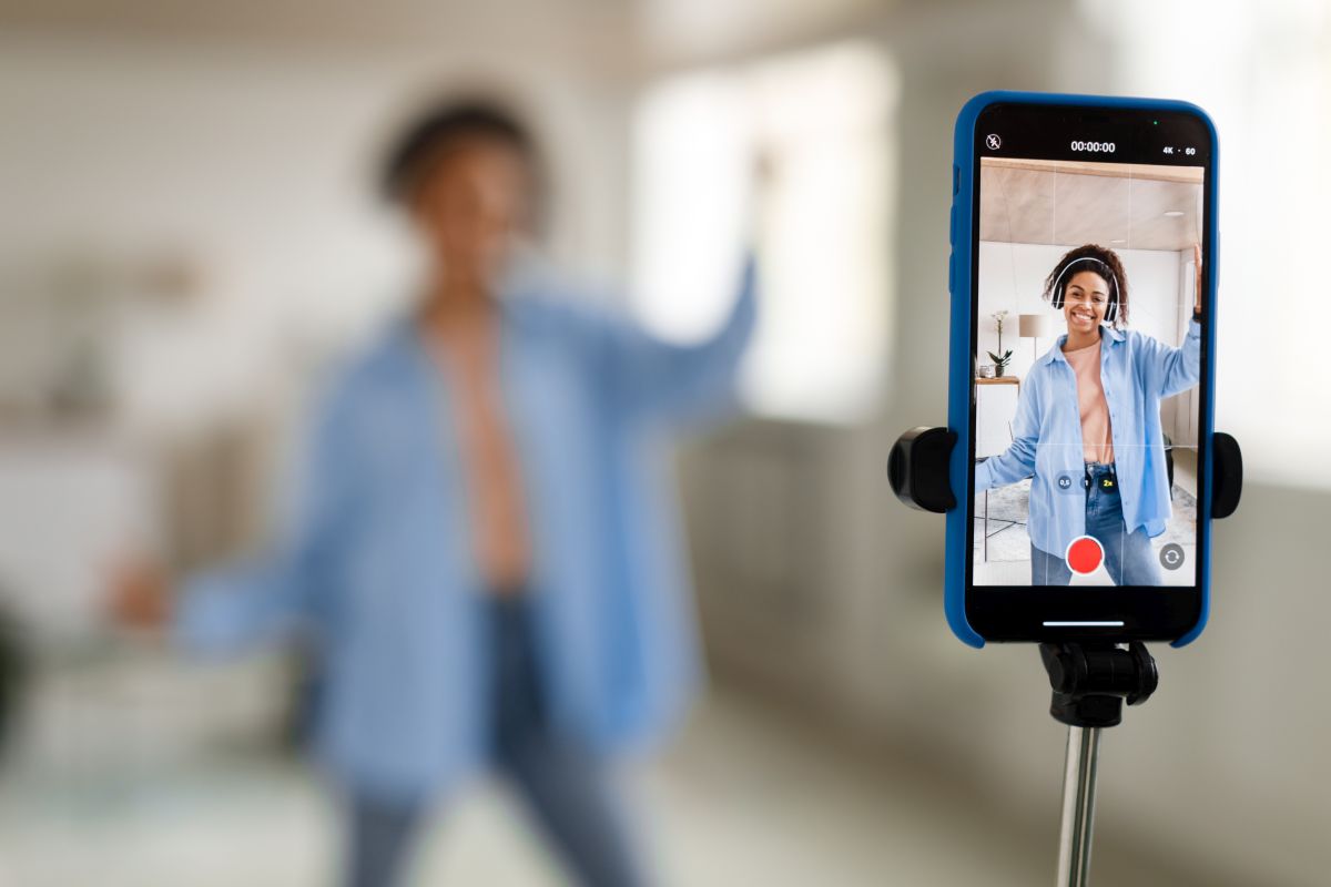 Cheerful black woman filming video on cellphone