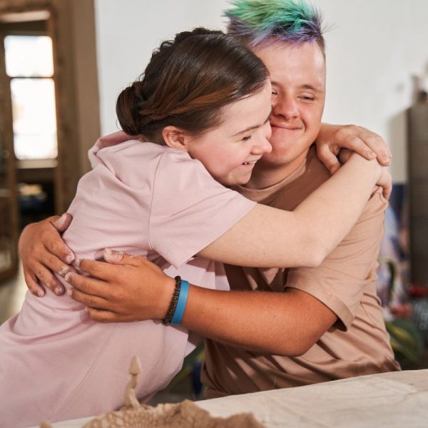 Ein junges Paar liegt sich in den Armen und lacht.